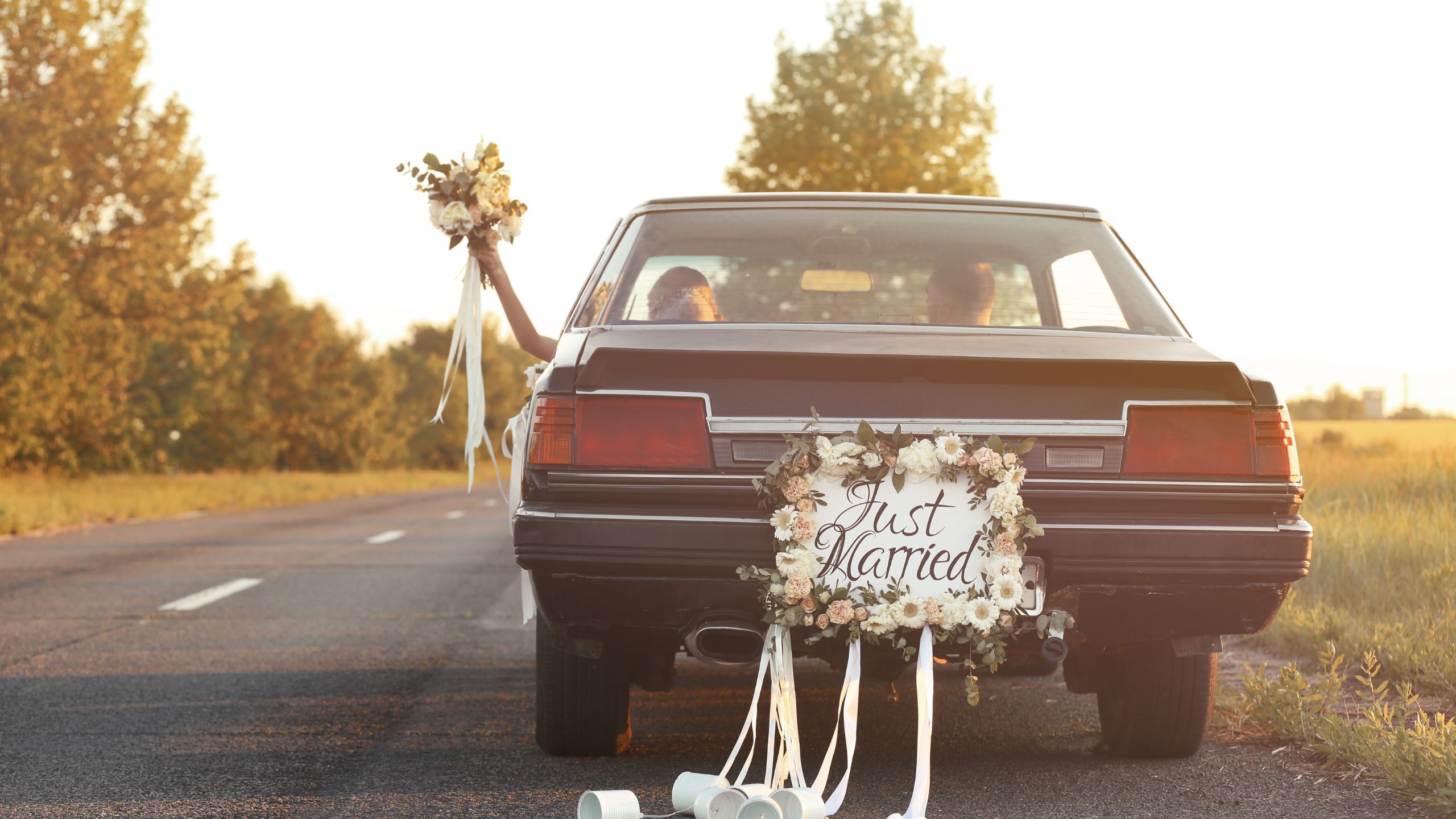 A dressed car with wedding ribbons containing couples who just got married